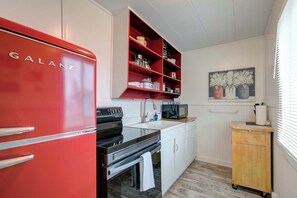 A compact kitchen with a red Galanz refrigerator, a microwave, a sink, and a wooden cabinet.