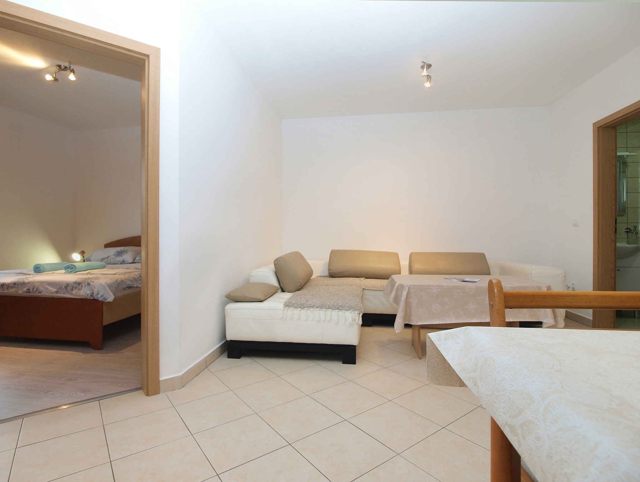 A compact room with a bed, a sofa, a small table, and a chair.