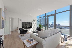 A modern living room with a large window, a flat-screen TV, and a sofa.
