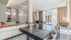 A modern hotel lobby with a glass conference table, comfortable seating, and large windows. - West Loop PH: Unmatched Views & Private Deck (Chicago)