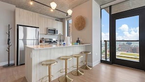 A modern kitchen with a central island, stainless steel appliances, and a view of the city through large windows. - West Loop 2BR, Walk to Top Restaurants, Sleeps 5 (Chicago)