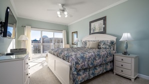 A bedroom with a bed, nightstands, a dresser, a ceiling fan, and a large window.