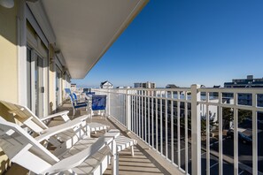 A balcony with white railings, a row of white lounge chairs, and a clear view of the cityscape. - New Listing! Beautiful 4 bedroom oceanblock condo with a pool! (Ocean City)