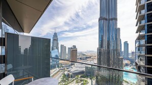 Balcó d'un edifici alt amb barana de vidre que ofereix vista a un paisatge urbà amb gratacels moderns i un front marítim.