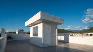 Una terraza en la azotea con una estructura blanca, una puerta y una ventana.
