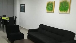 Una sala de estar moderna con un sofá negro, una mesa de centro y un comedor con una mesa amarilla y sillas negras.