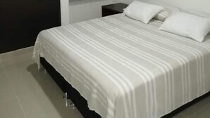 Un dormitorio con cama, mesita de noche, armario y aire acondicionado.