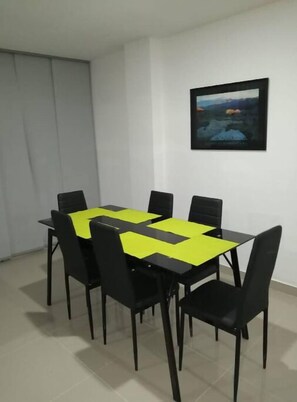 Un coin repas avec une table et des chaises, un tableau accroché au mur et une fenêtre avec des rideaux.