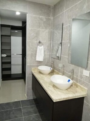 Une salle de bain moderne avec deux lavabos blancs, un grand miroir et un porte-serviettes.