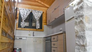 Cozinha compacta com armários de madeira, forno embutido e janela com cortinas.