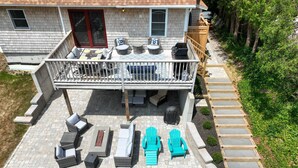 Un patio couvert avec des meubles d’extérieur, un barbecue et une terrasse en bois menant à la maison.