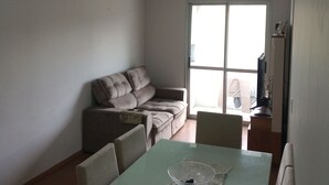 A living room with a sofa, a table with a crocheted table runner, and a ceiling light.