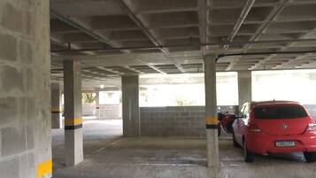 An underground parking garage with concrete pillars and a red car parked.