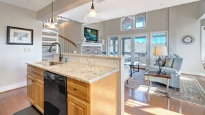 Une cuisine spacieuse dotée de plans de travail en granit, d’un lave-vaisselle et d’un four encastré. Un coin repas est aménagé avec un canapé et une table basse.