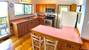 Une cuisine compacte avec des meubles en bois, un plan de travail rose et un four encastré.