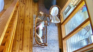 Un intérieur en bois aux plafonds hauts, avec un espace salon central comprenant un fauteuil suspendu et un fauteuil rembourré, de grandes fenêtres et une cheminée visible.