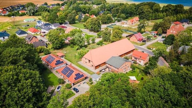 An aerial view of a rural area with a large red-roofed building labeled "KUSTENHUSSEL". - Küstenhostel (Klausdorf)