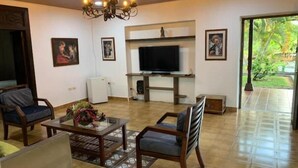 Ein Wohnzimmer mit Fernseher, Holzmöbeln und einem Kronleuchter.