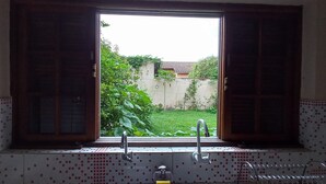 Une salle de bain avec une fenêtre, un lavabo et un mur recouvert de carreaux.