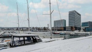 Un puerto deportivo con barcos amarrados, un edificio moderno con ventanas de vidrio y un cielo despejado.