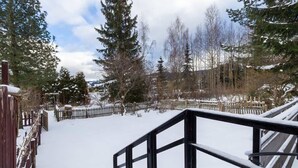 A snowy outdoor area with a wooden fence, snow-covered ground, and trees.