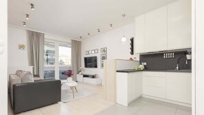 A modern apartment with a living area, kitchen, and a balcony with a view. - Elegant Apartment with Balcony | Close to the Airport (Warszawa)