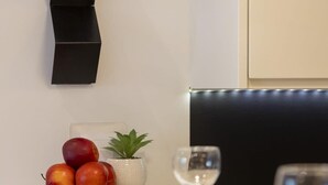 A modern dining area with a wooden table set for two, featuring white plates, two wine glasses, and a small potted plant. - Elegant Apartment with Balcony | Close to the Airport (Warszawa)