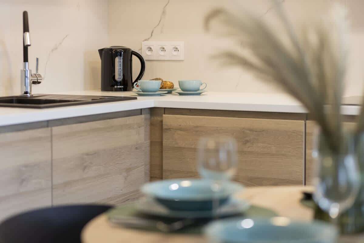 A modern kitchen with a sink, a coffee maker, and a small dining area with a table and chairs.