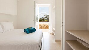 A hotel room with a bed, a blue towel, and a view of the outdoors through an open door. - My Rental Homes - Villa Panita with swimming pool private garden wifi (Ostuni)