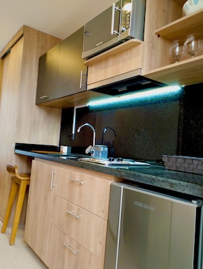 A modern kitchen with wooden cabinets, a stainless steel dishwasher, and a black countertop.