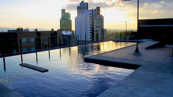 Una piscina en la azotea con un paisaje urbano de fondo.