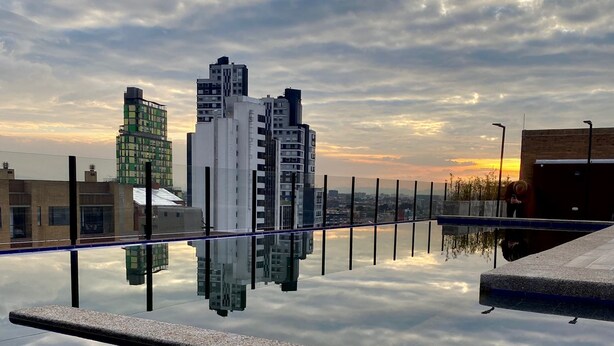 A rooftop terrace with a clear view of surrounding buildings and a sunset in the background. - ApartaSuite Spa Work Bogota  (Bogotá)