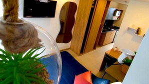 A modern room with a bed, a hanging plant, a TV, and a kitchen area. - ApartaSuite Spa Work Bogota  (Bogotá)