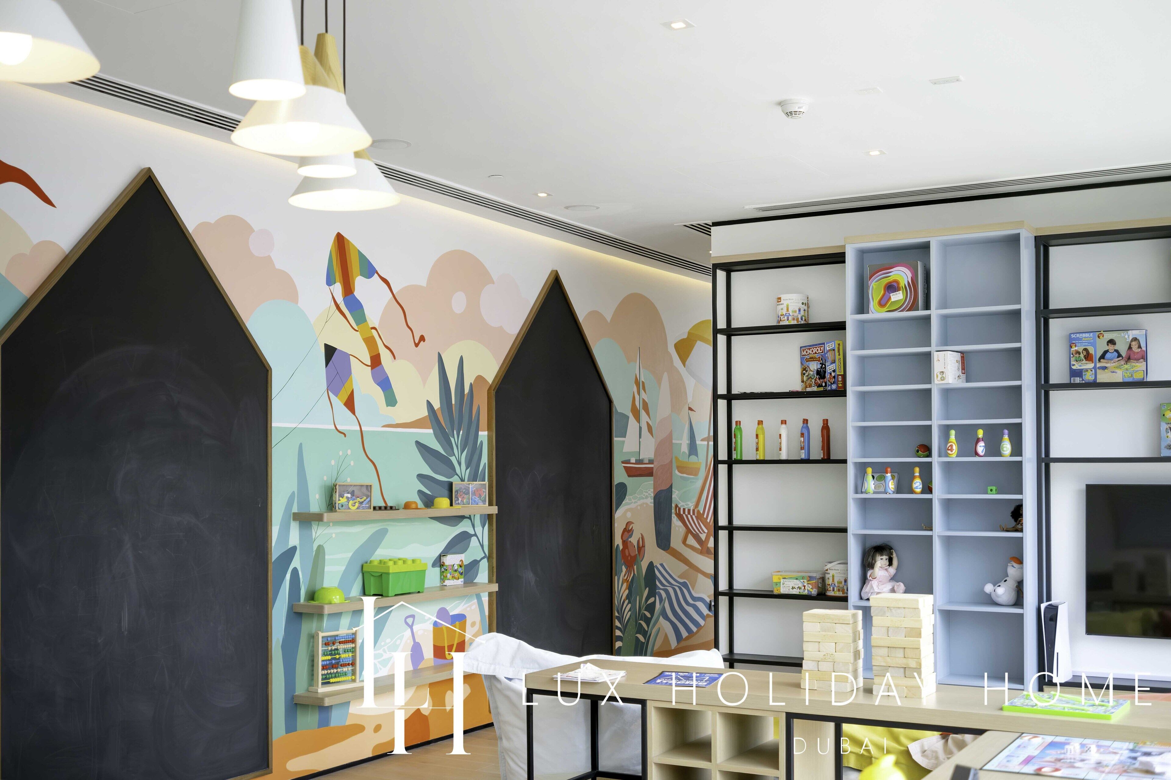 A children's play area with colorful murals, shelves with toys, and a chalkboard.