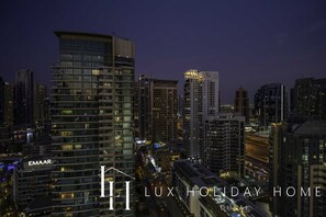 Un immeuble de grande hauteur, doté de nombreux étages, arborant un grand panneau distinctif d'EMAAR, et offrant une vue sur un paysage urbain animé, avec d'autres bâtiments imposants et une autoroute.