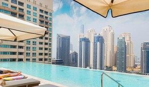 Une vue sur la piscine, avec des chaises longues et, en arrière-plan, le panorama de la ville.