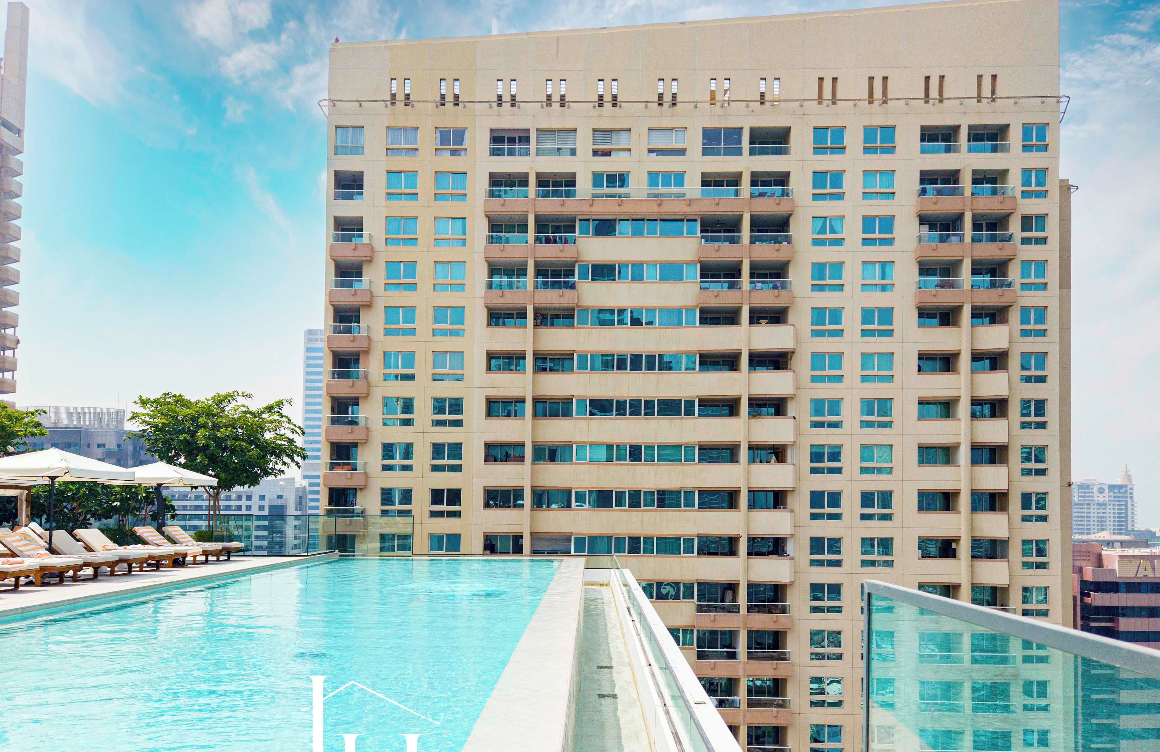 A high-rise building with a swimming pool and sun loungers.