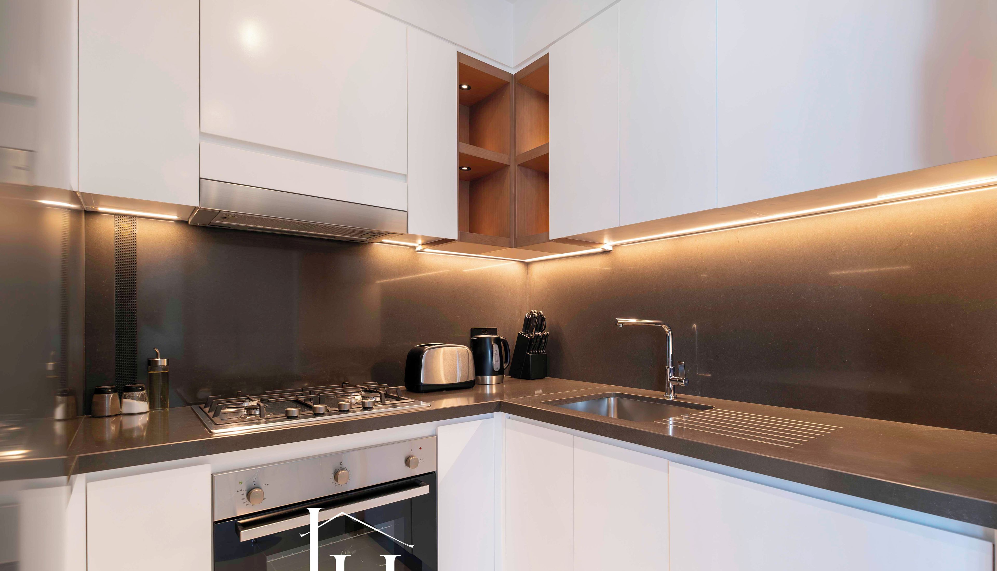 A modern kitchen with stainless steel appliances, white cabinetry, and a sleek countertop.