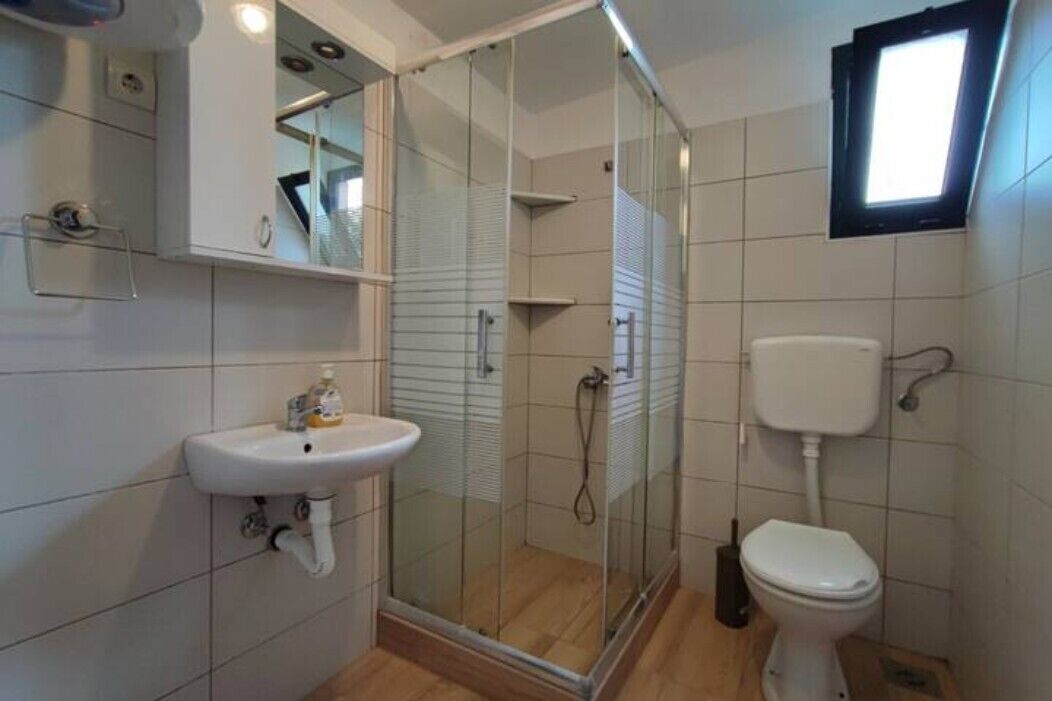 A bathroom with a glass-enclosed shower, a white sink, and a toilet.