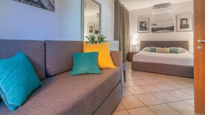 A modern hotel room with a sofa, a bed, a mirror, and artwork on the walls. - The Patio Over Varenna (Perledo)