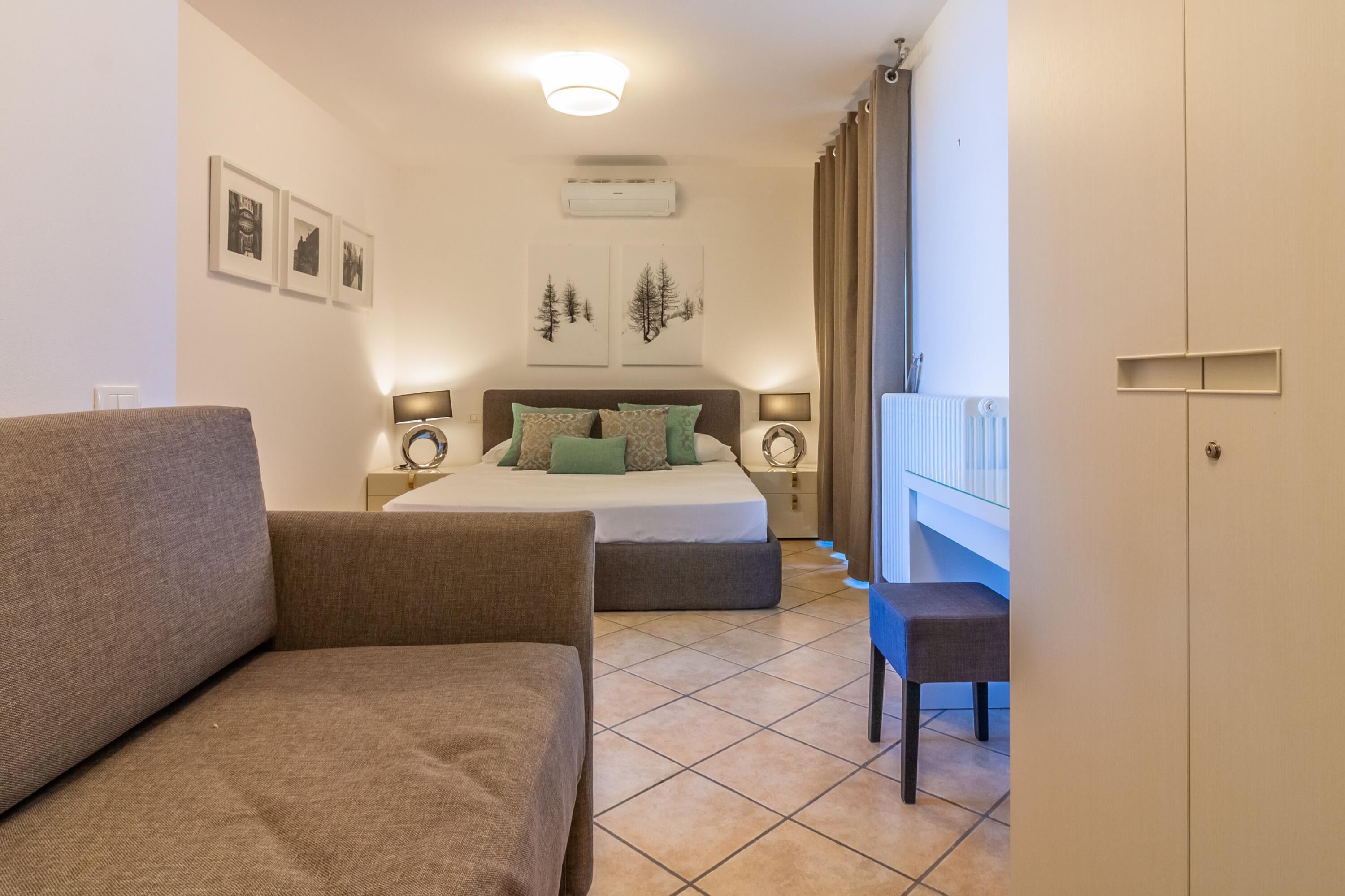 Un dormitorio con cama, sofá, escritorio y armario.