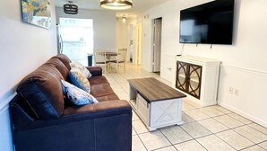 Ein modernes Wohnzimmer mit einem braunen Ledersofa, einem Holztisch und einem flachbildfernseher an der Wand.