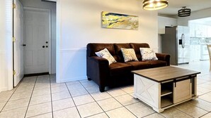 Ein Wohnzimmer mit braunem Ledersofa, einem Holztisch und einer modernen Pendelleuchte.