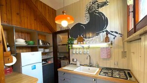 A compact kitchen with wooden cabinets, a gas stove, a sink, and a refrigerator.