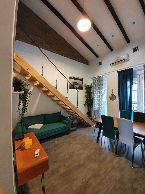 Relax in this spacious living area with a loft-style design, featuring a sofa and dining space.
