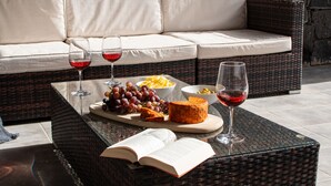 A wicker table with a book, cheese, grapes, and wine glasses. - Casa Marlay Spacious Villa Pool, BBQ & Fast Wi-fi Sun all day (Playa Blanca)