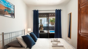 A hotel room with a bed, a view of a pool, and a wooden door. - Casa Marlay Spacious Villa Pool, BBQ & Fast Wi-fi Sun all day (Playa Blanca)
