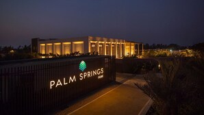 A modern hotel with a well-lit entrance and a sign that reads "PALM SPRINGS Hotel". - Palm Springs Resort (Nashik)
