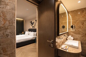 A hotel room with a bed, a bathroom with a large mirror, and a marble wall. - Palm Springs Resort (Nashik)