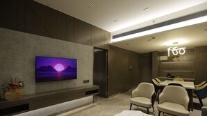 A modern interior with a flat-screen TV on a wall, a dining area with chairs and a table, and a decorative vase on a console. - Palm Springs Resort (Nashik)